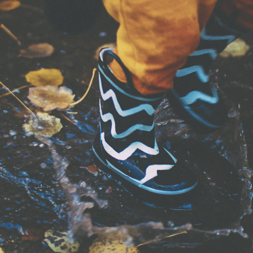 Photo: Child's rain boot splashing in a puddle