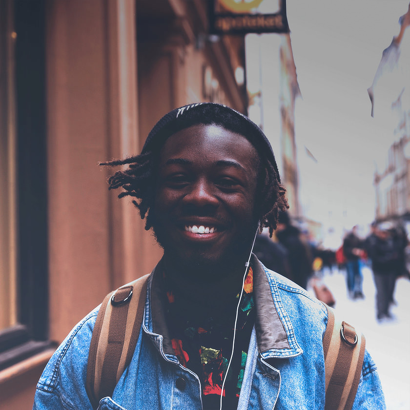Photo: Smiling man on street wearing headphones